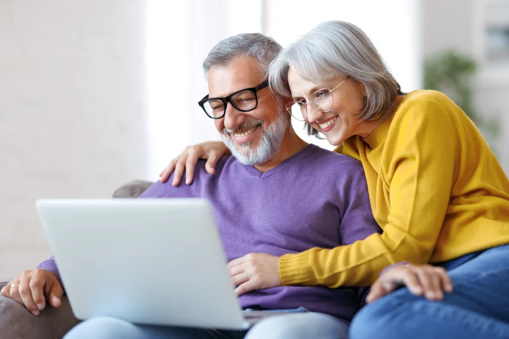 Older couple scheduling hearing test on laptop
